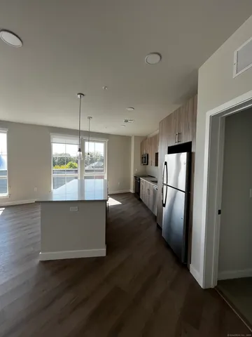 a open kitchen with stainless steel appliances a refrigerator and wooden floor