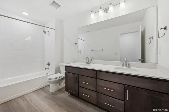 a bathroom with a double vanity sink toilet mirror and bathtub