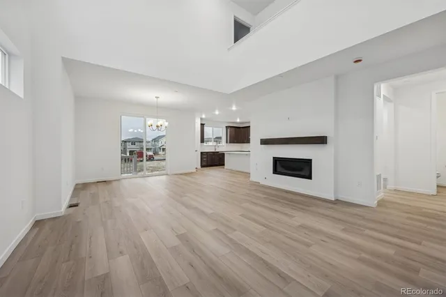 a view of a livingroom with a fireplace a ceiling fan and wooden floor