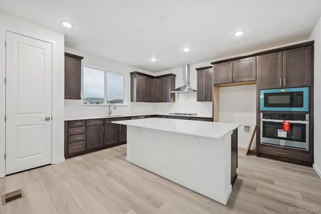 a kitchen with stainless steel appliances kitchen island granite countertop a refrigerator and a stove top oven