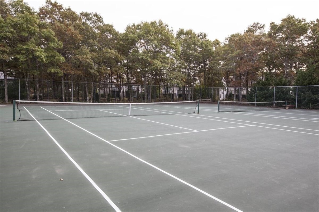 141 Great Neck Road South, Unit 203 Mashpee, MA 02649 - Photo 14 of 16 a view of tennis court with trees in the background