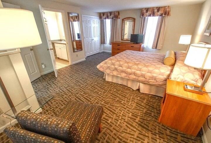 141 Great Neck Road South, Unit 203 Mashpee, MA 02649 - Photo 7 of 16 a bedroom with a bed a mirror on dresser and a large window