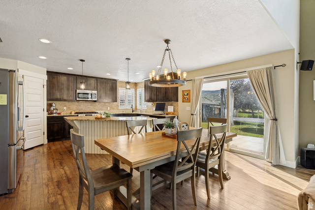 Kitchen featuring wood-finish flooring, dark wood cabinetry, a center island with a light-colored countertop, and a sliding glass door