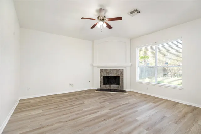 a view of empty room with wooden floor and fan