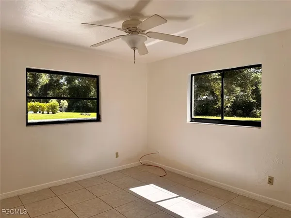 an empty room with wooden floor and ceiling fan
