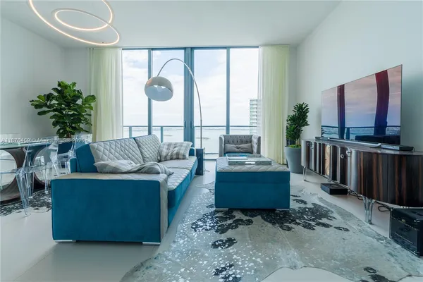 a living room with furniture a flat screen tv and a large window