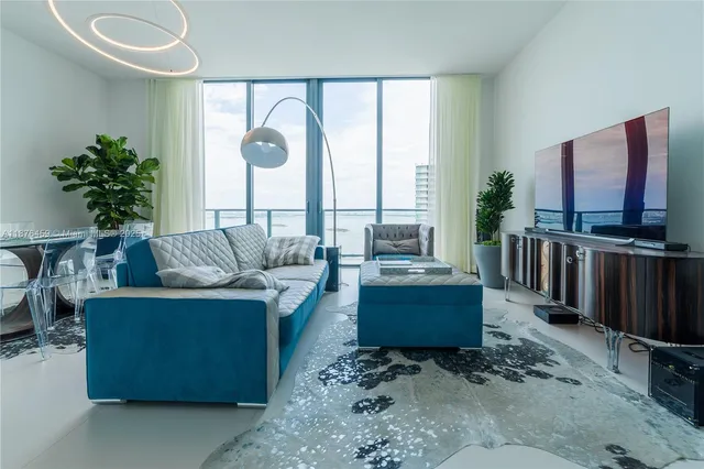 a living room with furniture a flat screen tv and a large window