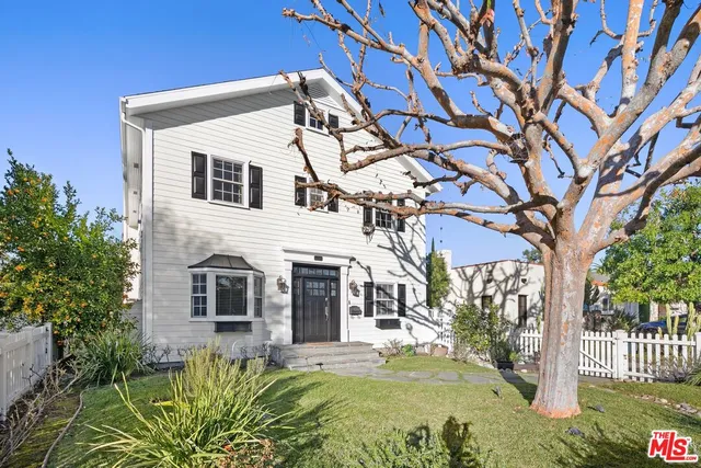 a view of a white house with a large tree