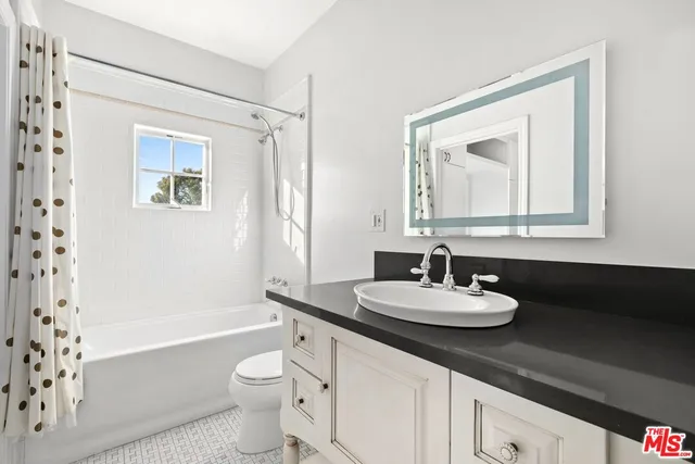 a bathroom with a bathtub a sink a mirror a toilet and a window