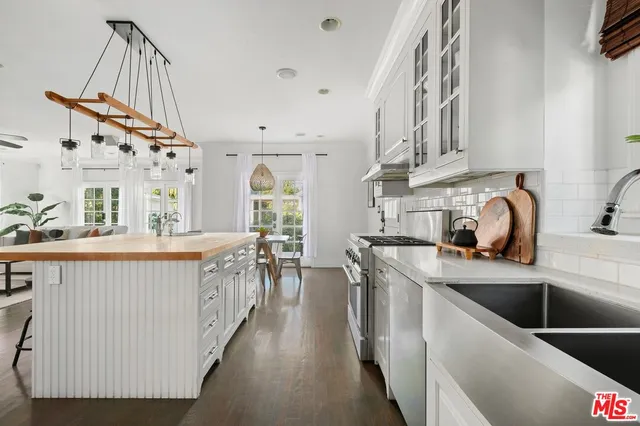 a kitchen with stainless steel appliances granite countertop a sink a stove and a wooden floors