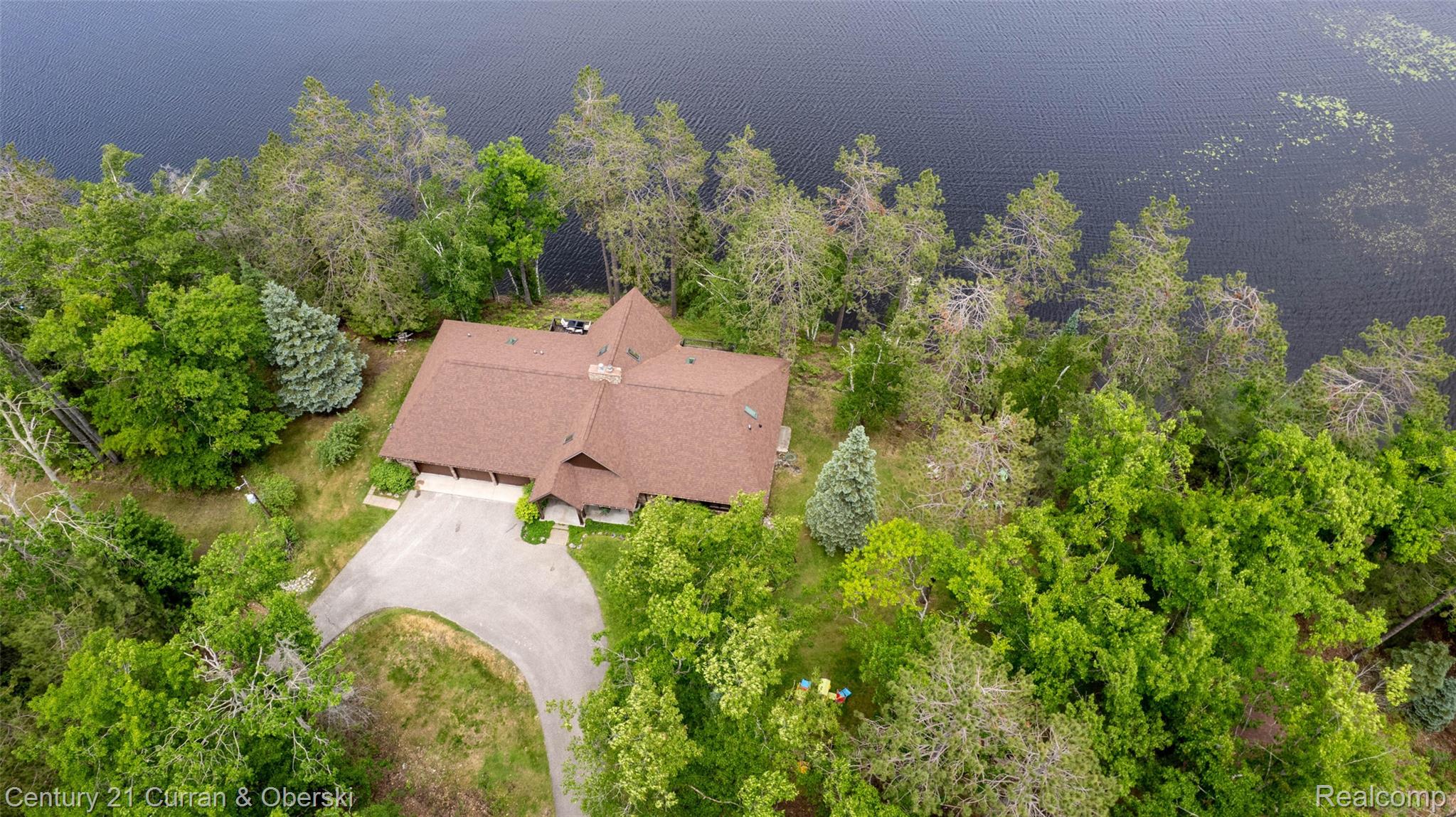 8775 Winding Rdg Drive Millersburg, MI 49759 - Photo 5 of 53 Waterfront property featuring a distinctive brown-shingled roof and a paved circular driveway