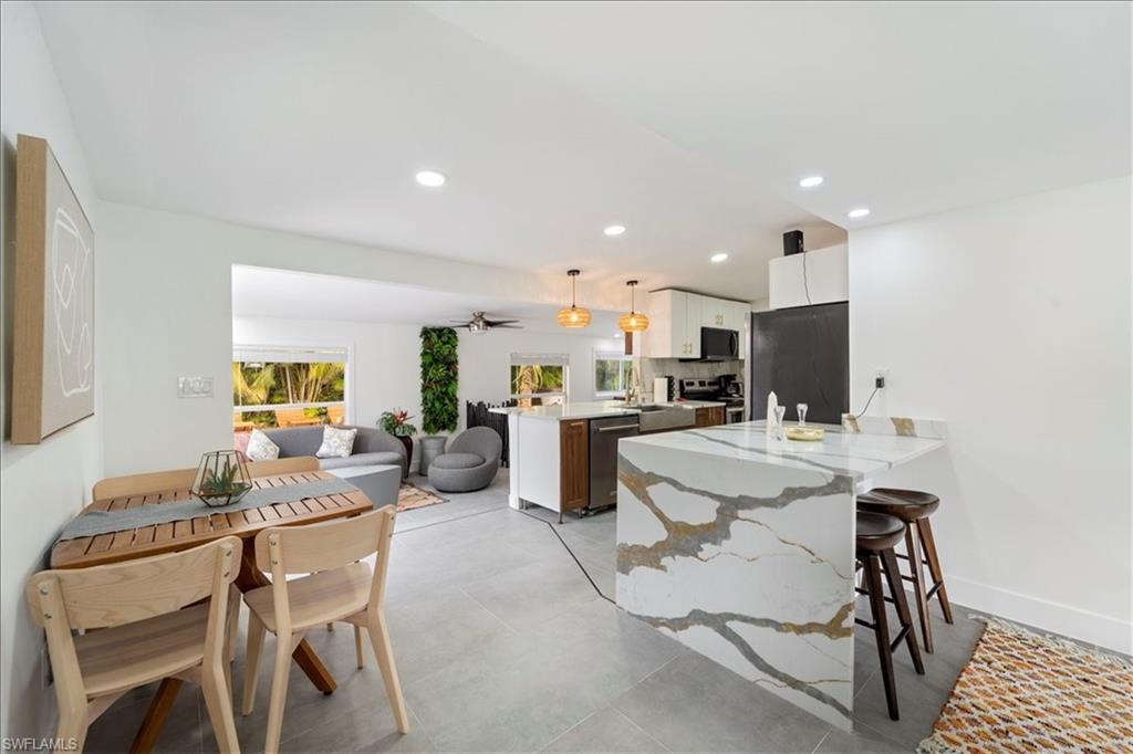 2123 Holiday Lane Naples, FL 34104 - Photo 6 of 43 a kitchen with a dining table chairs and white cabinets