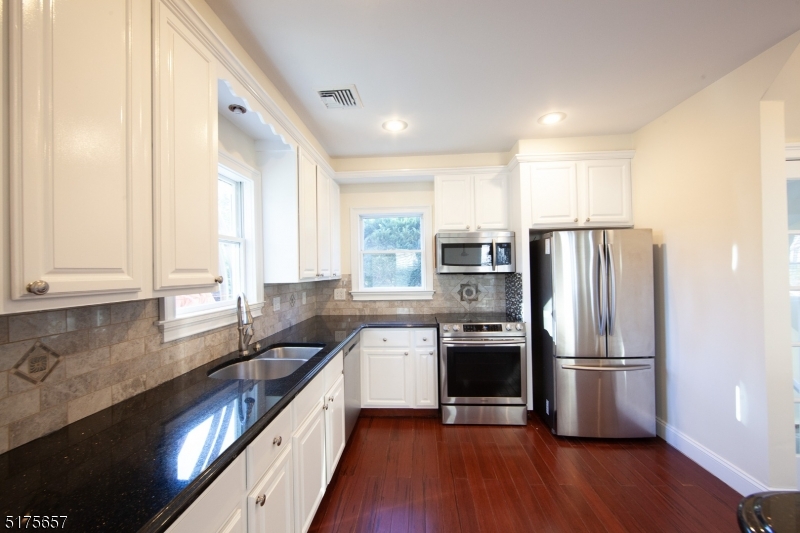 16 Columbus Avenue Glen Ridge, NJ 07028 - Photo 13 of 14 a kitchen with stainless steel appliances granite countertop a refrigerator a sink dishwasher a stove and white countertops with wooden floor