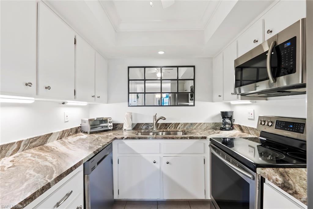 136 Harrison Road, Unit 1 Naples, FL 34112 - Photo 9 of 29 Galley kitchen featuring white cabinetry, stone-finish countertops, and stainless steel appliances