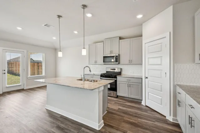 a kitchen with stainless steel appliances granite countertop a sink a stove and a refrigerator