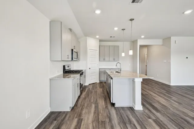 a kitchen with stainless steel appliances wooden floors stove and white cabinets