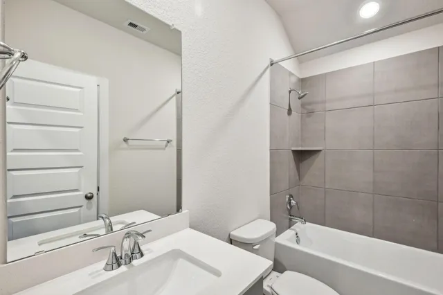 a bathroom with a bathtub shower sink vanity and toilet