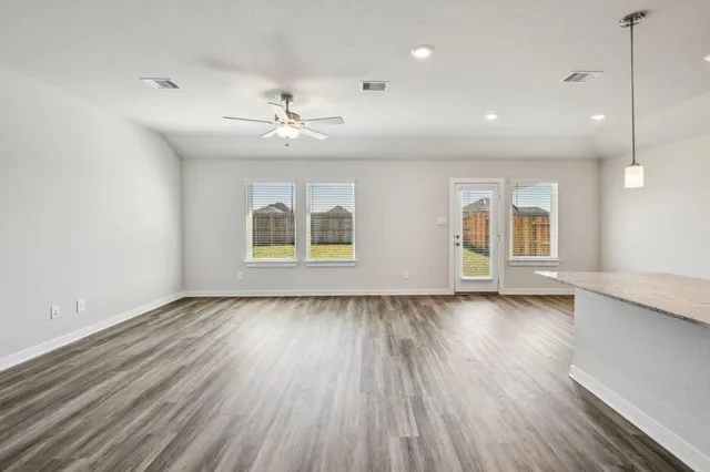 an empty room with wooden floor chandelier and windows