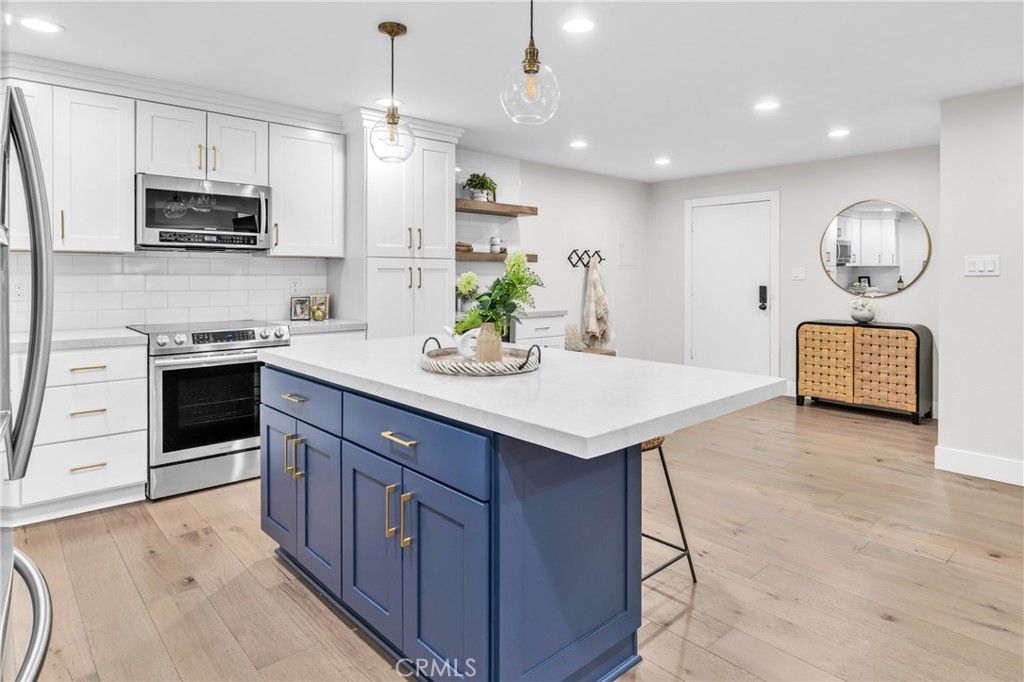 a kitchen with stainless steel appliances a sink a stove a microwave a center island and cabinets