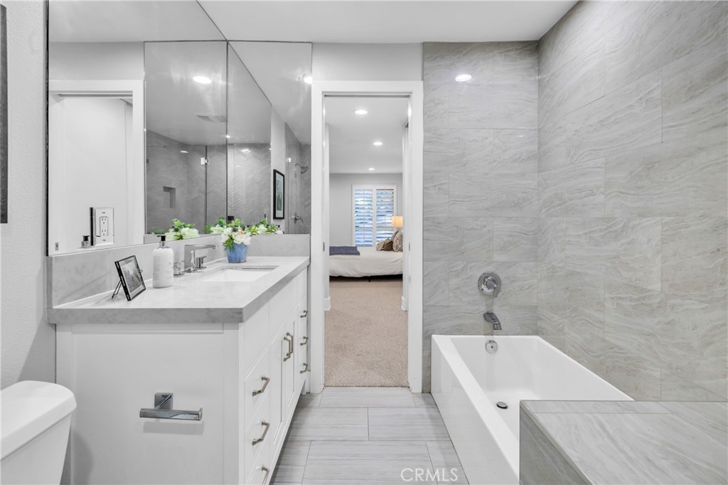 7890 East Spring Street, Unit 10F Long Beach, CA 90815 - Photo 19 of 31 a bathroom with a double vanity sink a toilet and a bathtub