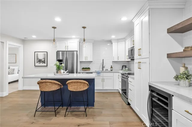 a open kitchen with stainless steel appliances granite countertop a kitchen island a stove a refrigerator a sink dishwasher a dining table and chairs with wooden floor