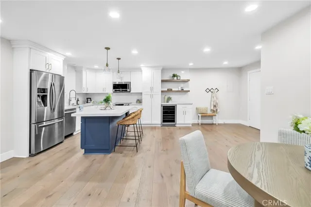 a kitchen with stainless steel appliances kitchen island granite countertop a refrigerator a stove top oven a sink dishwasher and white cabinets with wooden floor