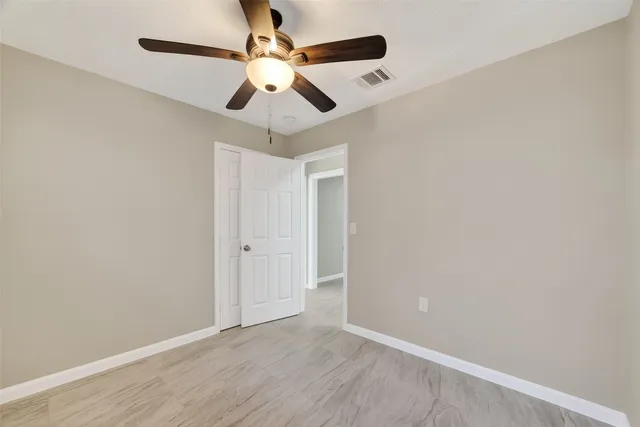 an empty room with a window and a ceiling fan