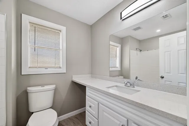 a bathroom with a toilet a sink a mirror and a window