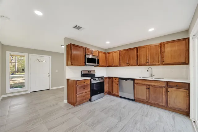 a large kitchen with stainless steel appliances granite countertop a stove top oven a sink dishwasher and a microwave oven on the wooden floor