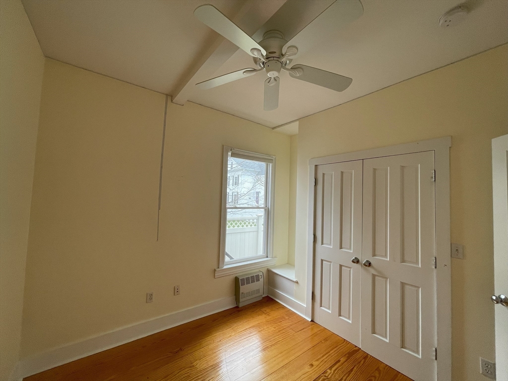 22 Walnut Place, Unit 1 Newton, MA 02460 - Photo 5 of 9 an empty room with wooden floor fan and windows