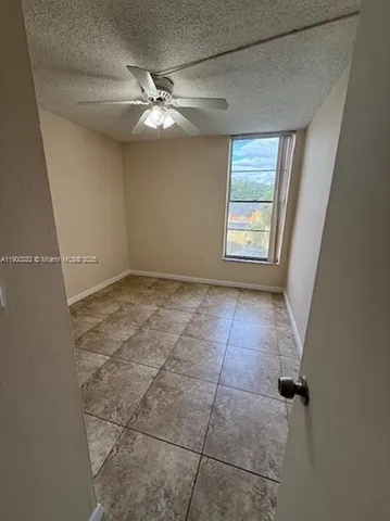 an empty room with windows and fan