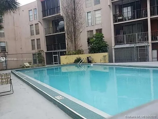 a view of pool with outdoor seating and house in the background