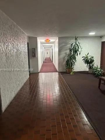 a view of a hallway with wooden floor and a potted plant