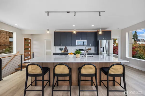 a kitchen with stainless steel appliances granite countertop a dining table chairs refrigerator and sink