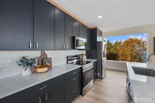 a kitchen with stainless steel appliances kitchen island granite countertop a sink dishwasher stove and cabinets with wooden floor