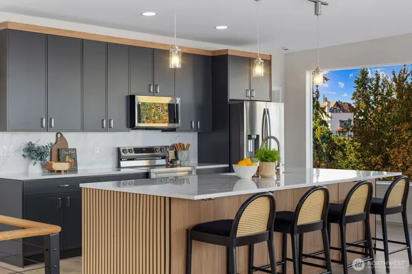 a kitchen with stainless steel appliances granite countertop a table chairs in it and wooden floors