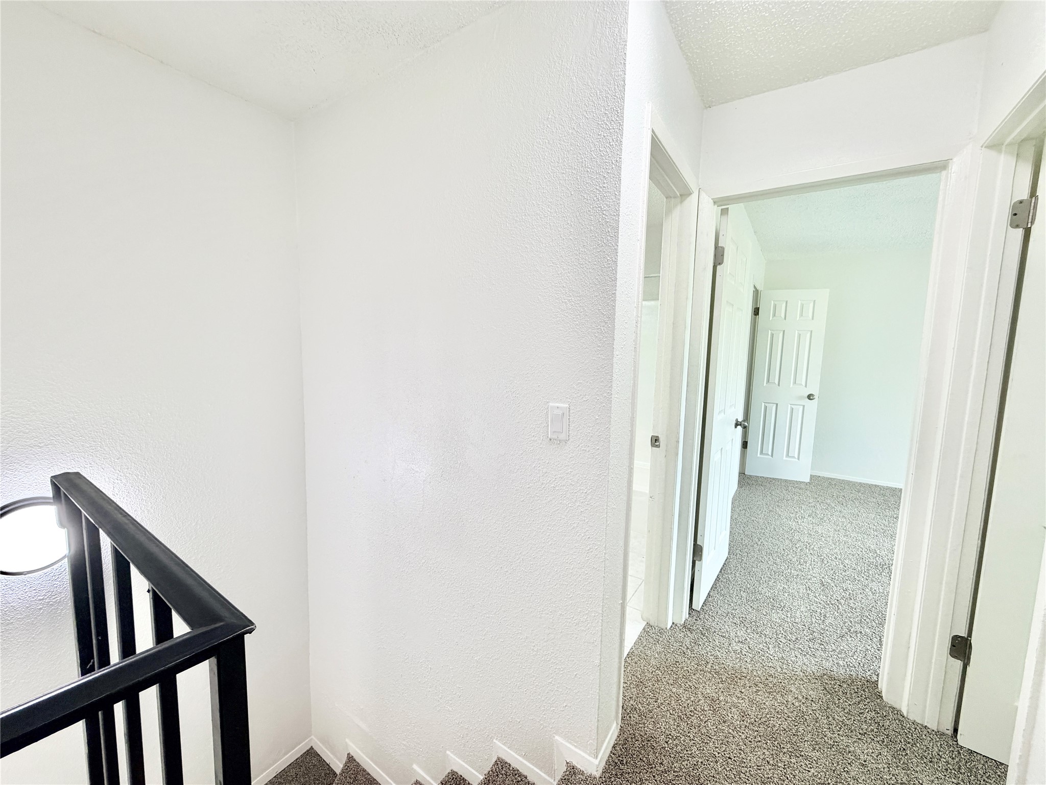 9623 Covey Ridge Lane Austin, TX 78758 - Photo 23 of 40 Hallway with light colored carpet, a textured ceiling, an upstairs landing, and a textured wall