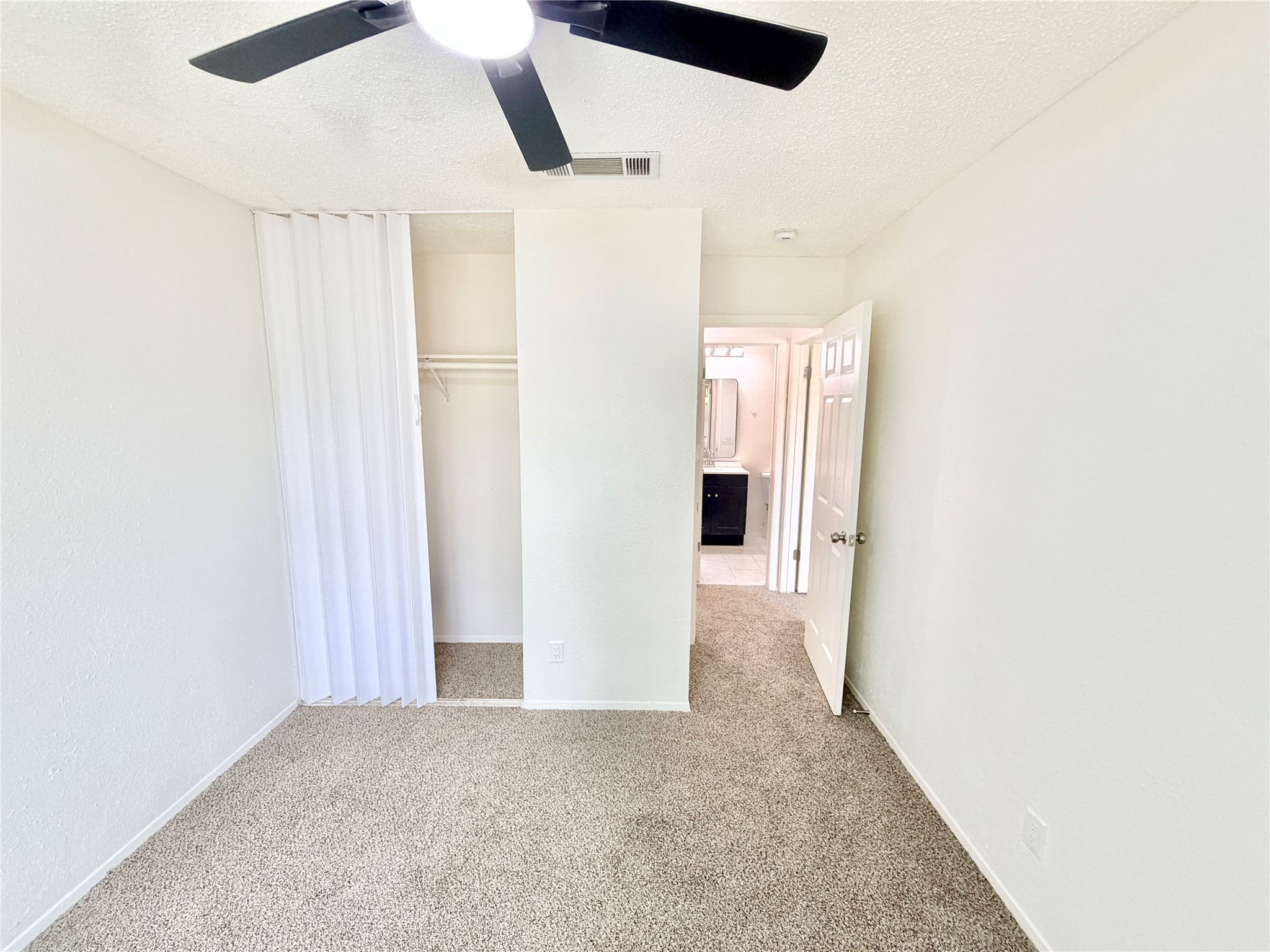 9623 Covey Ridge Lane Austin, TX 78758 - Photo 28 of 40 Unfurnished bedroom with a textured ceiling, light carpet, a closet, and ceiling fan