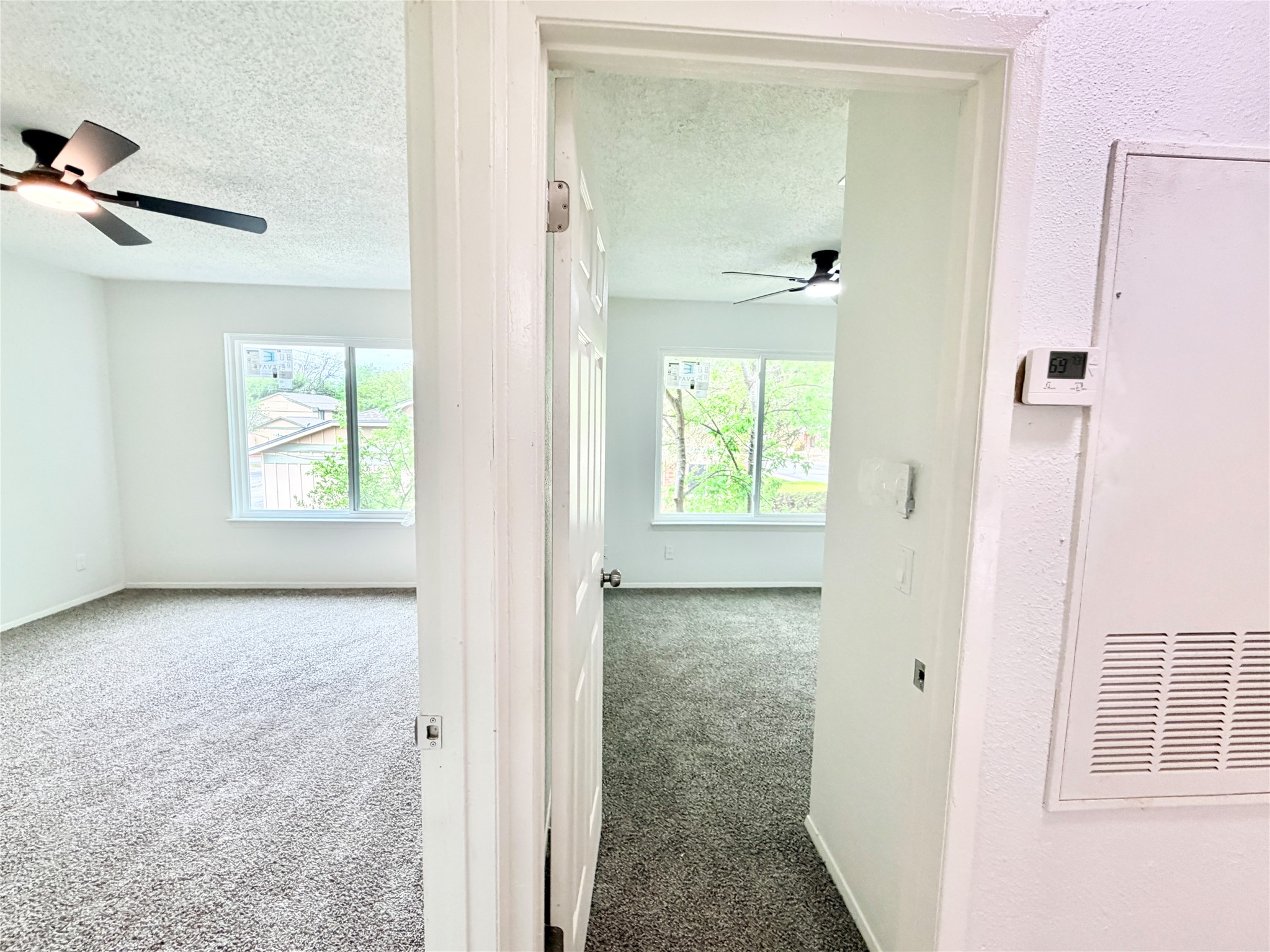 9623 Covey Ridge Lane Austin, TX 78758 - Photo 32 of 40 Hallway featuring dark carpet, a textured ceiling, a heating unit, and plenty of natural light