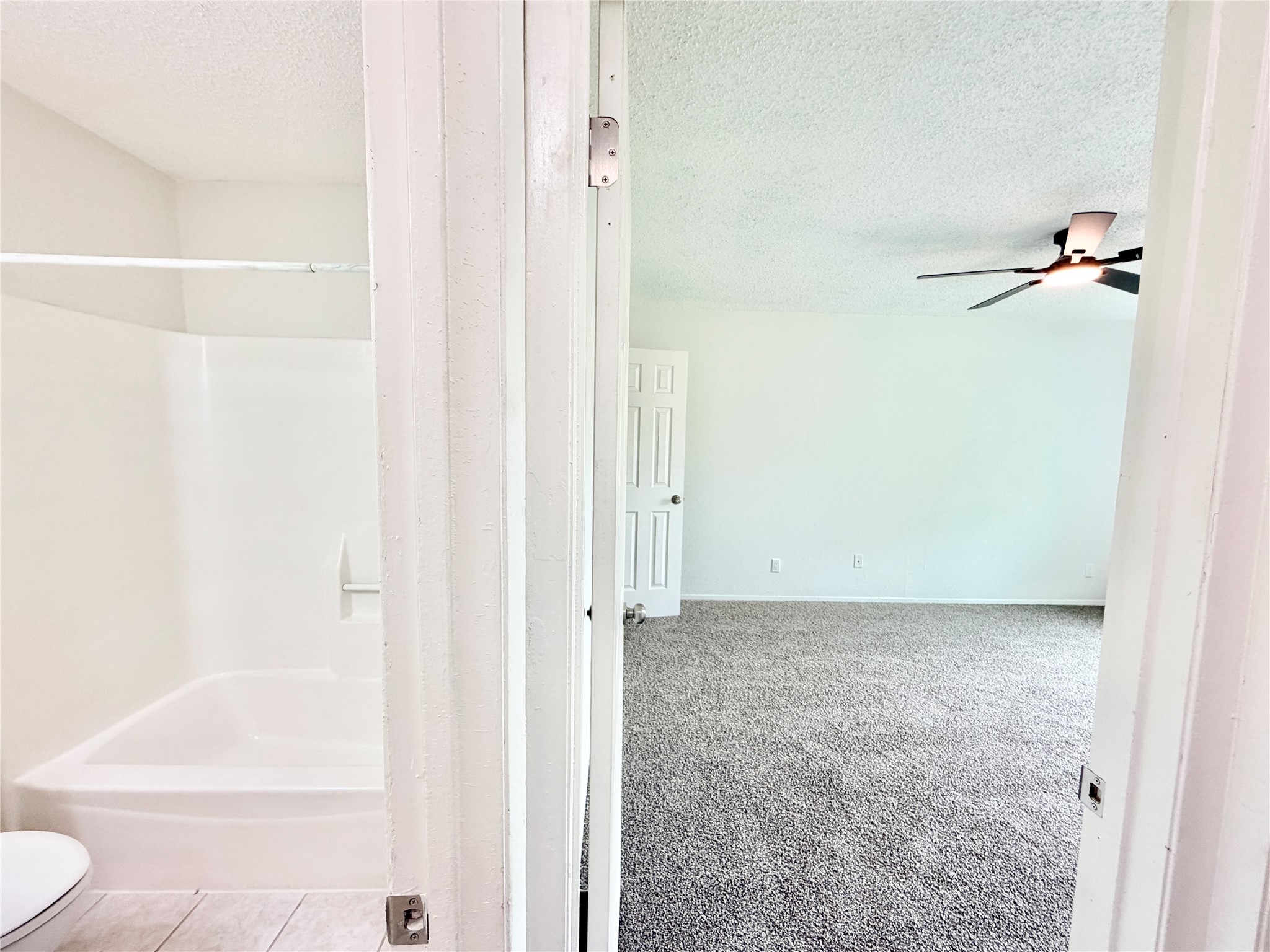 9623 Covey Ridge Lane Austin, TX 78758 - Photo 37 of 40 Bathroom with a textured ceiling, tub / shower combination, a ceiling fan, and light carpet
