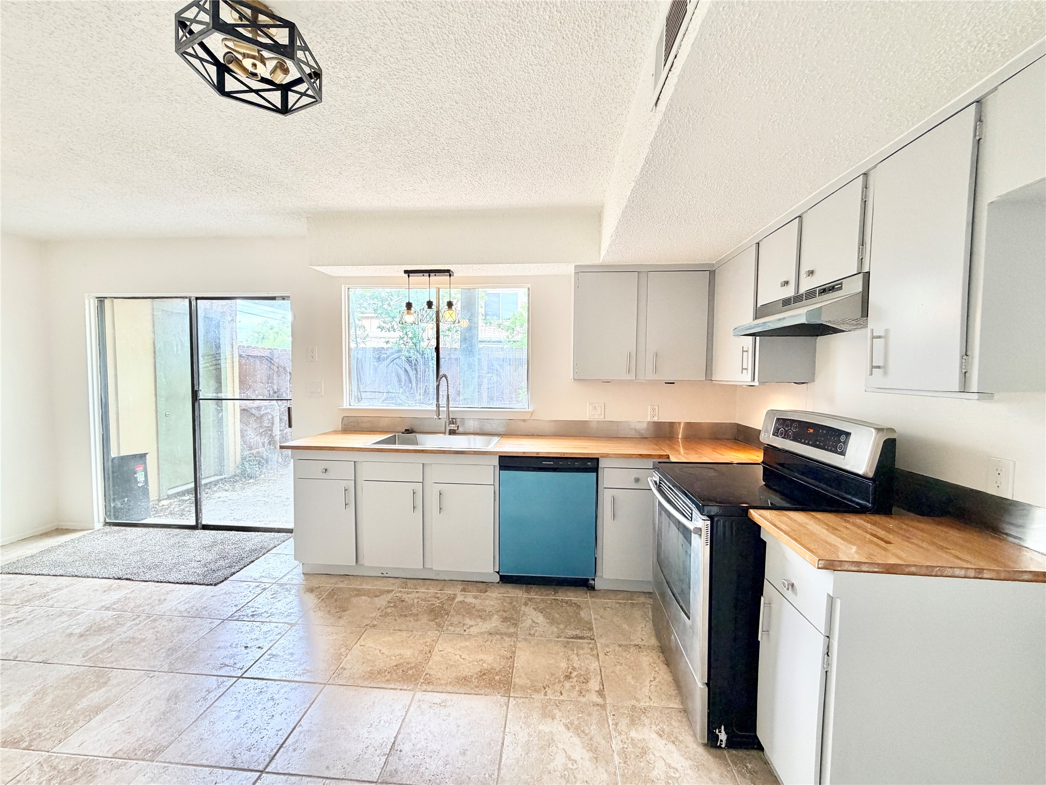 9623 Covey Ridge Lane Austin, TX 78758 - Photo 9 of 40 Kitchen with stainless steel range with electric cooktop, dishwashing machine, hanging light fixtures, a textured ceiling, and gray cabinets
