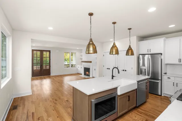 a kitchen with stainless steel appliances granite countertop a sink a stove and a wooden floors