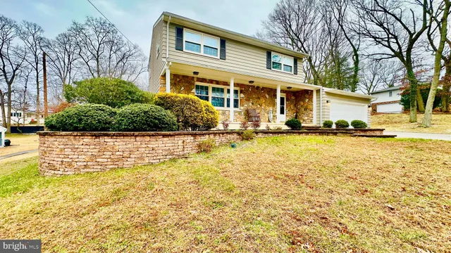 a front view of a house with a yard with plants and large tree
