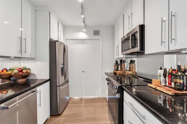 a kitchen with stainless steel appliances granite countertop a refrigerator a stove and a sink with cabinets