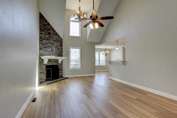 a view of an empty room with wooden floor fireplace and a window