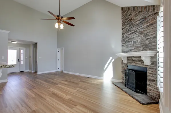 an empty room with wooden floor fireplace and windows