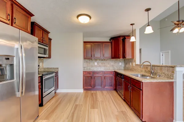 a kitchen with stainless steel appliances granite countertop a stove a sink dishwasher a refrigerator and a oven with wooden floor