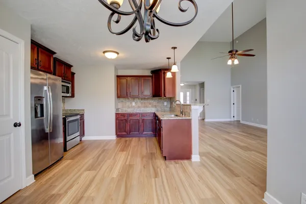 a kitchen with stainless steel appliances kitchen island granite countertop a refrigerator a oven a sink and blue cabinets with wooden floor