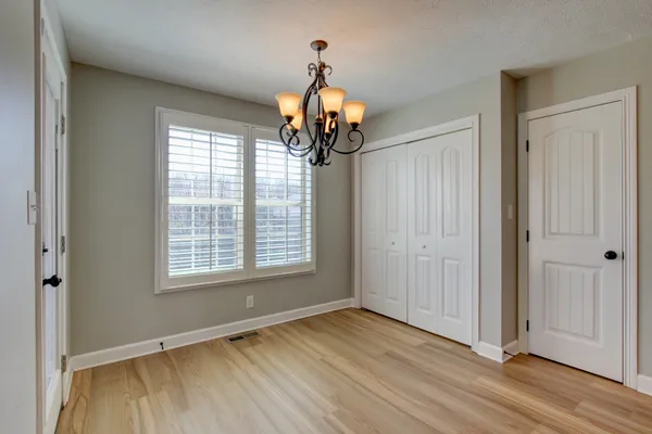 a view of a room with wooden floor chandelier and windows