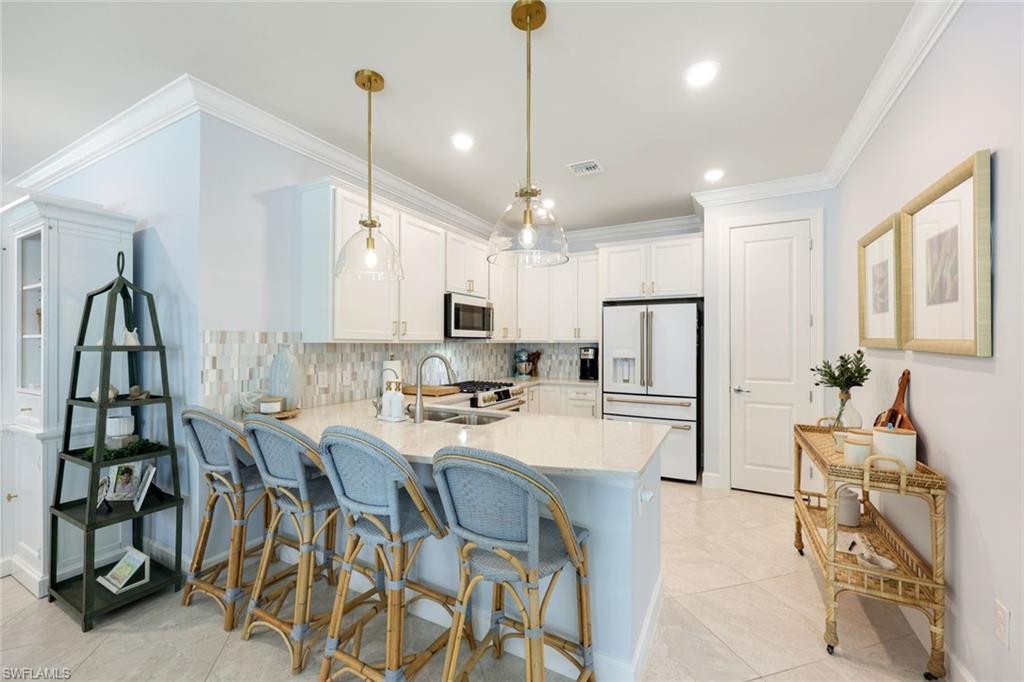 10763 Manatee Key Lane Estero, FL 33928 - Photo 5 of 33 a kitchen with a table chairs refrigerator and microwave